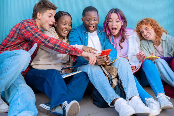 istock A group of diverse young people smiling sitting outdoors using smart phones 2176388619