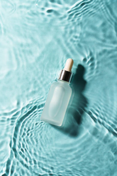 Serum bottle in the water on blue. Flat lay with copy space.