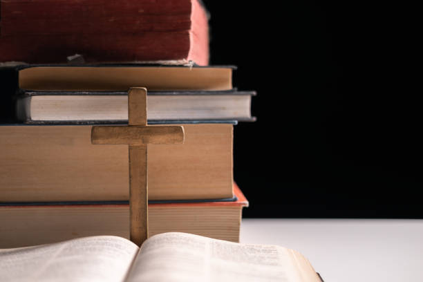 istock Old library, an open Bible lay on the table, its holy pages of scripture illuminated in the dark room. bible, holy, dark, old, open, library, pages, scripture, table, book, page. 2176394890