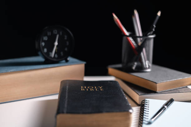 istock Old library, an open Bible lay on the table, its holy pages of scripture illuminated in the dark room. bible, holy, dark, old, open, library, pages, scripture, table, book, page. 2176394933