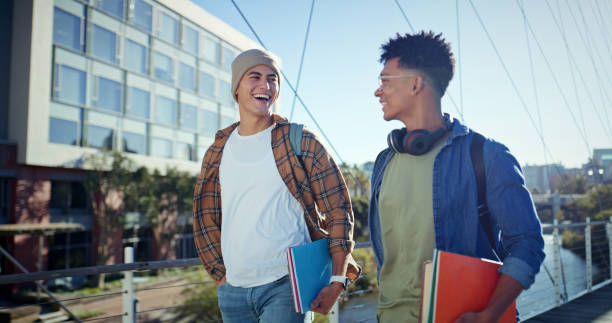 istock Walking, students and men with education, talking and funny with humor, joke and learning. Campus, happy people and friends with smile, university and joyful with conversation, knowledge and college 2176396444