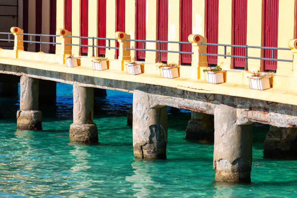Serene pier featuring a wooden bench overlooking calm sea water. Terrace on the water on Mondello beach in Palermo