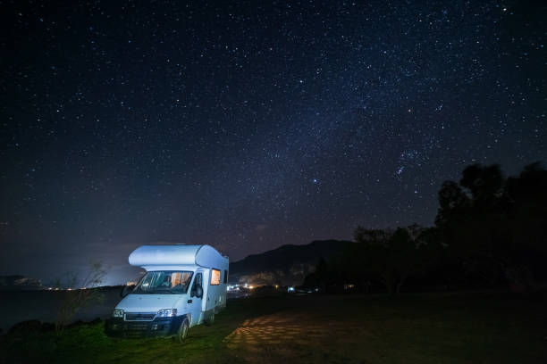 istock Serene night sky over camper van under a star-filled sky on a tranquil lakeside, showcasing a perfect van life evening 2176403757