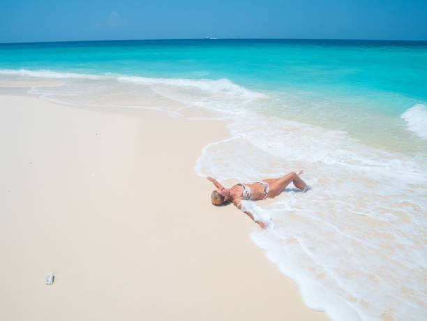 Woman in swimwear  sunbathing and enjoy sunny summer day on sand beach