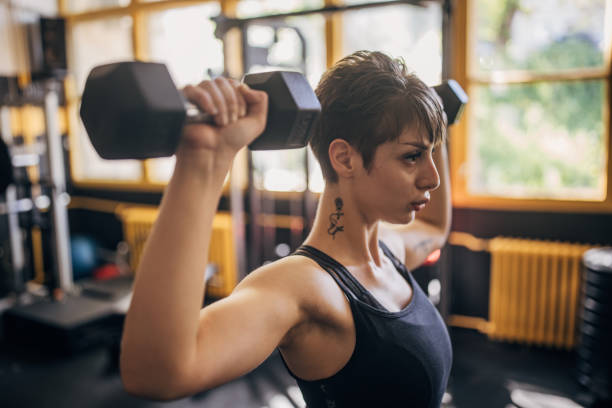 Woman training with dumbbells, exuding determination.