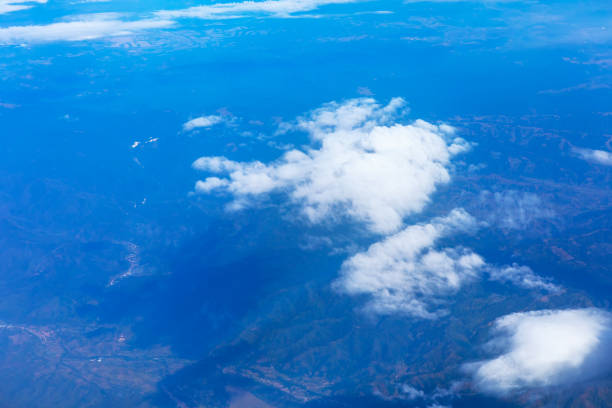 Aerial view of clouds at blue background. View from airplane window. Fluffy white clouds stretching across the blue sky