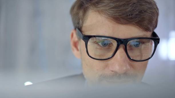 istock Businessman with glasses looking intently obscured partially by a translucent surface of laptop. Business concept 2176423002