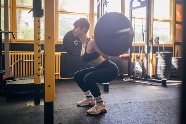 istock Woman mastering gym squat with heavy barbell weights 2176423015