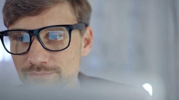 istock Businessman with glasses looking intently obscured partially by a translucent surface of laptop. Business concept 2176423845