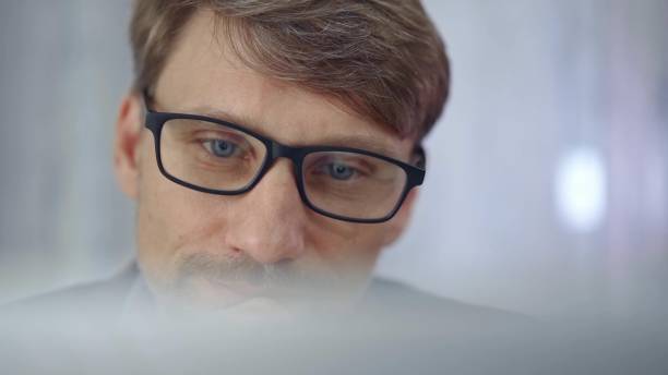 istock Businessman with glasses looking intently obscured partially by a translucent surface of laptop. Business people concept 2176425249
