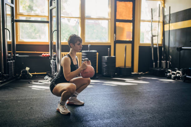 istock Squatting with kettlebell in sunlit gym environment 2176427778