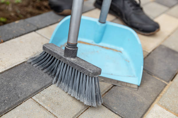 istock Person sweeping a paved area with a broom and dustpan. The broom is sweeping up some debris that has fallen onto the paved area. Cleaning and tidying, tidying up. 2176427962
