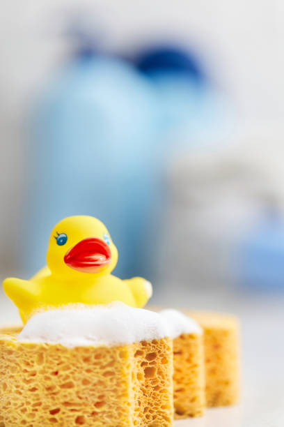 Yellow rubber duck, soap, bath foam on bath background, baby bath accessories