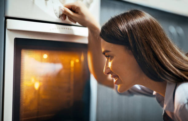 istock Cheerful housewife baking lunch in oven, setting temperature 2176429830