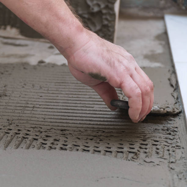 istock Construction worker applies cement for laying floor ceramic tiles with spatula 2176429872
