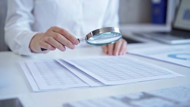 istock Businesswoman with white blues is analyzing financial data on a spreadsheet using a magnifying glass. Audit and taxes 2176430982