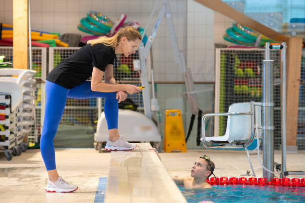 Asian chinese personal trainer showing his student on stopwatch time record at pool side during sport training