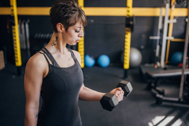 istock Focused woman lifting dumbbell in gym environment 2176431275