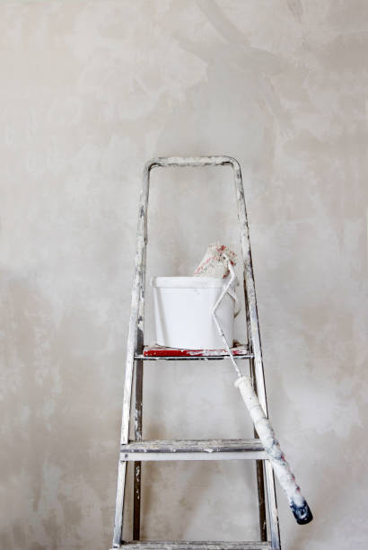 istock A white paint bucket with a used roller, positioned on a spattered paint step ladder against the concrete unpainted wall. Home renovation DIY essential tools. Minimalistic concept. Copy space. 2176433400