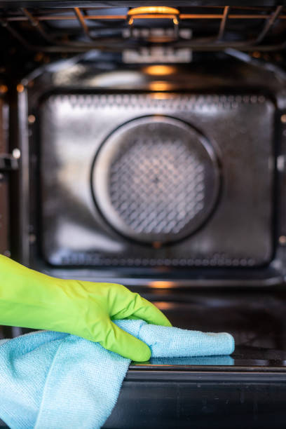 istock Hand in green cleaning glove wipes down inside empty oven 2176436268