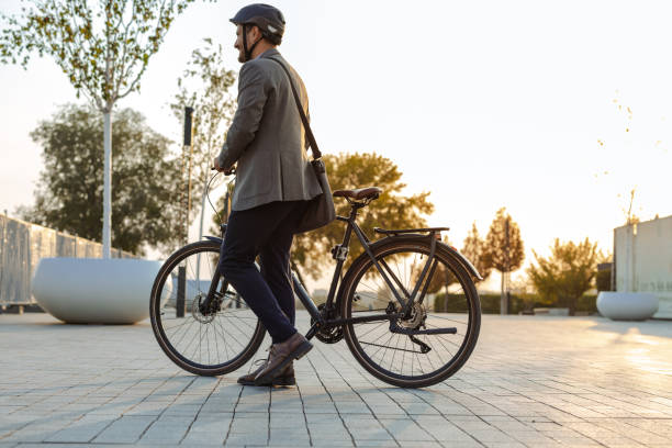 istock Businessman walking with bicycle in urban setting at sunset 2176438521