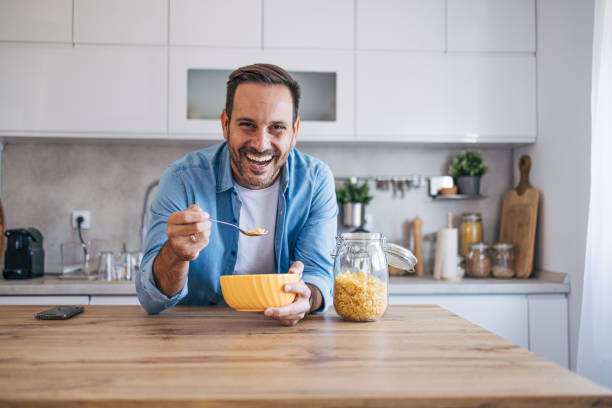 istock A mid-adult, cheerful, handsome man enjoying breakfast in the kitchen. 2176447854