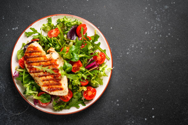 istock Green salad with chicken and fresh vegetables on black background. 2176448376