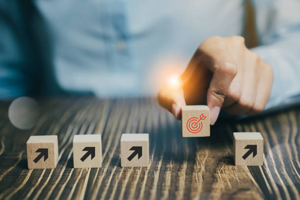 istock A hand selecting a block with a target symbol from a set of directional blocks on a wooden surface. 2176451727