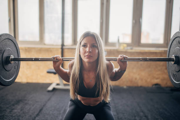 istock Woman lifting barbell in intense gym workout session. 2176454948