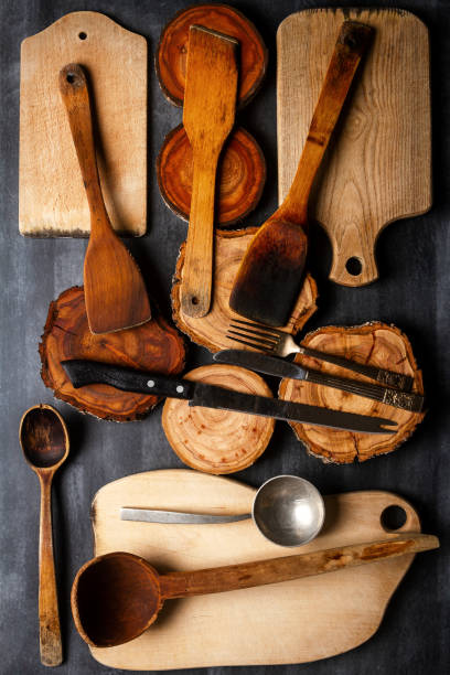 istock Old wooden cutting boards, tree trunk slices and kitchen utensils on black chalkboard 2176456407