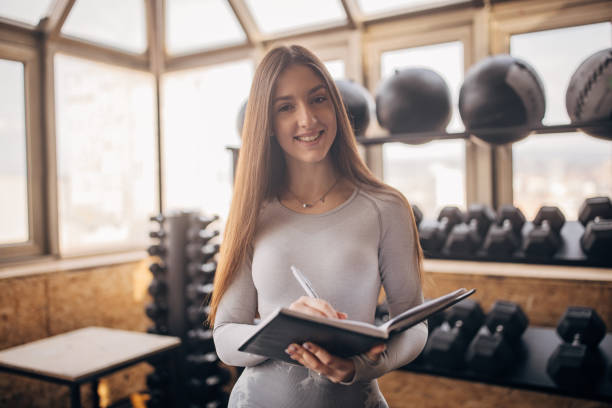 istock Woman smiling in gym holding a notebook 2176457897