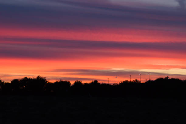 Bright high contrast colours of reds and pinks in a cloudy sky during dusk, seen from a field near Bristol Airport.