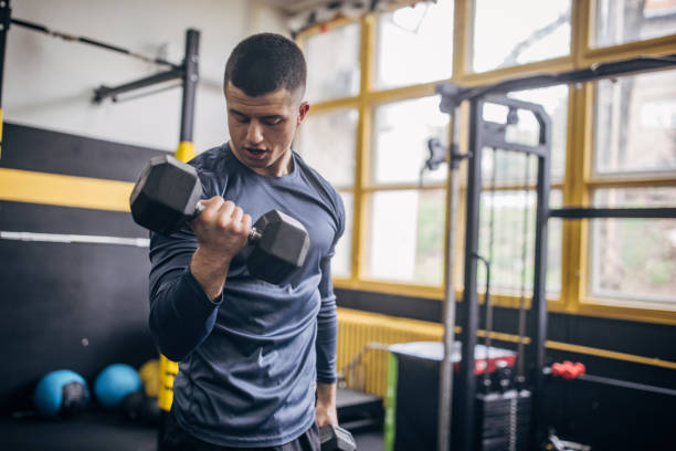 istock Man lifting dumbbell in modern gym environment. 2176467208