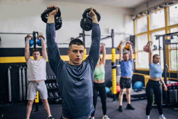 istock Man leading kettlebell workout in vibrant gym space. 2176467418