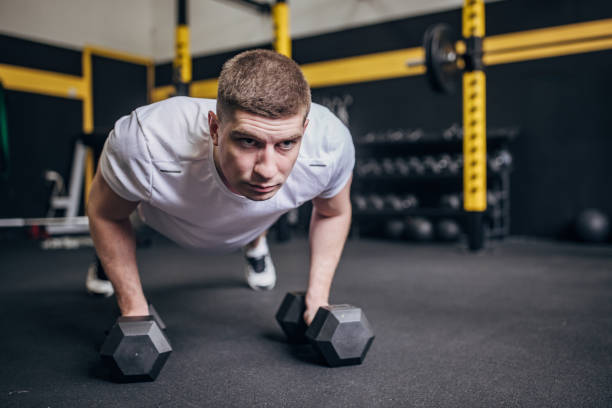 istock Man in gym performing dumbbell push-up exercise. 2176467754