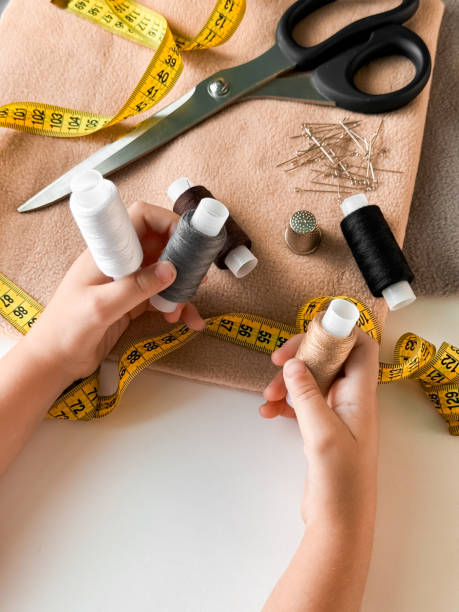 istock Hands holding thread and sewing tools on fabric with measuring tape and scissors 2176468741