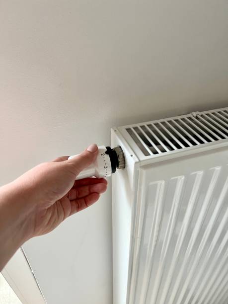 istock A woman's hand switches the temperature on the radiator 2176469005