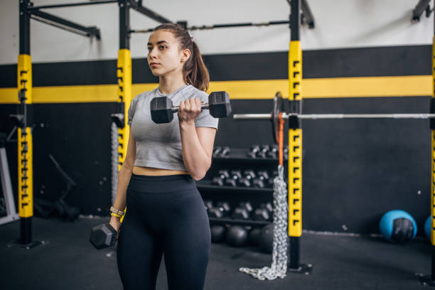 istock Strong woman lifting dumbbell in modern gym setting. 2176471855