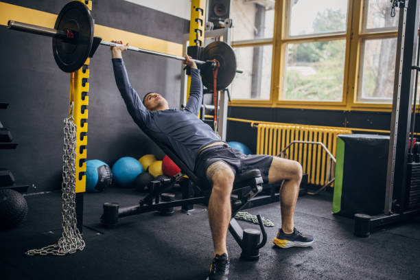istock Person in blue shirt doing bench press in bright gym. 2176474062