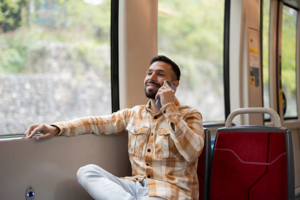 istock A man in a casual plaid shirt, enjoying a conversation on his phone while sitting on a train. 2176475885