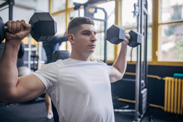 istock Man performing shoulder workout with heavy dumbbells 2176476583