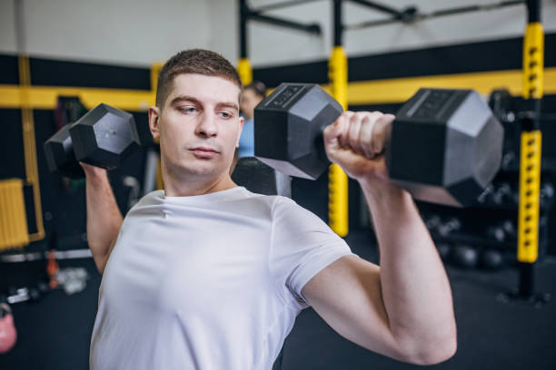 istock Man performing dumbbell shoulder presses in gym 2176476723