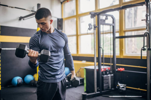 istock Man performing dumbbell curls in a modern gym. 2176476776
