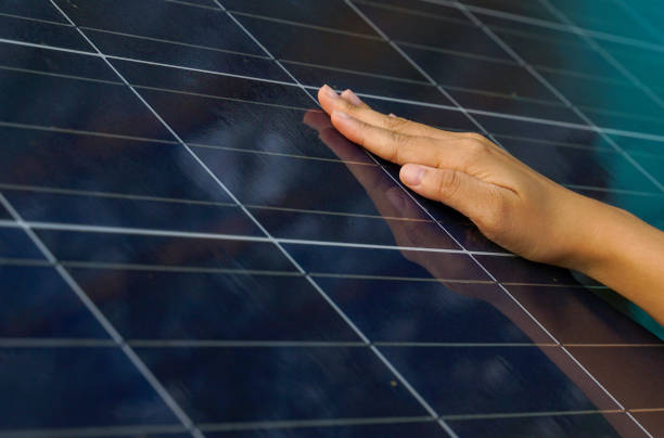 Closeup hand on photovoltaic or solar cell panel, soft and selective focus on hand, self-photovoltaic panel checking by touch the surface, concept, renewable energy,global warming