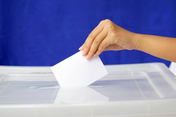 Hand drops a ballot into a box. Soft and selective focus. In the concept of voting system, voting, election, Members of the House of Representatives vote.