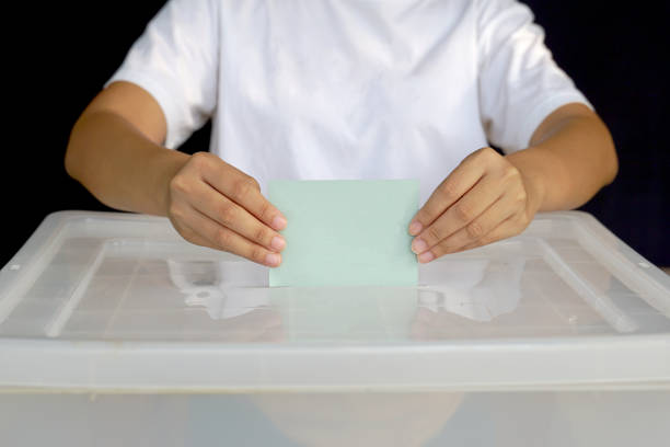 Hand drops a ballot into a box. Soft and selective focus. In the concept of voting system, voting, election, Members of the House of Representatives vote.