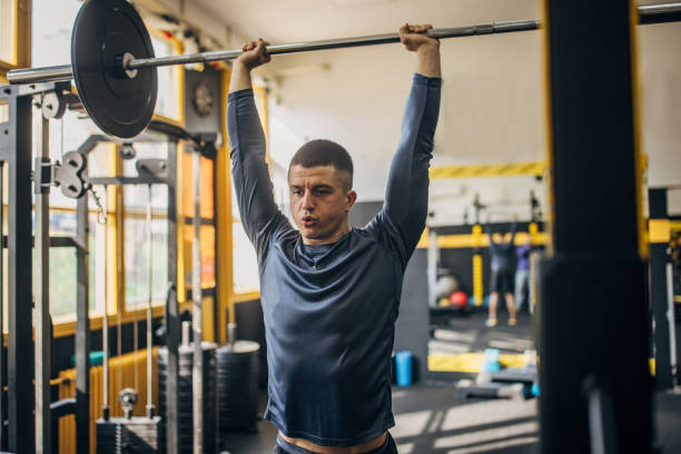 istock Man lifting weights in a gym with determined focus. 2176478610