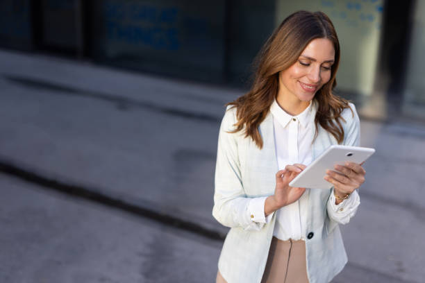 istock Businesswoman browsing on her tablet in a modern cityscape 2176478781