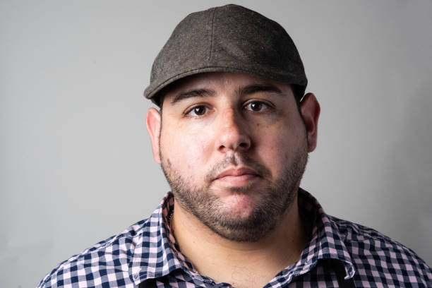 Serious man wearing a cap looking at the camera on gray background