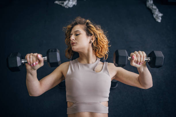 Woman performing bench press exercise with dumbbells.